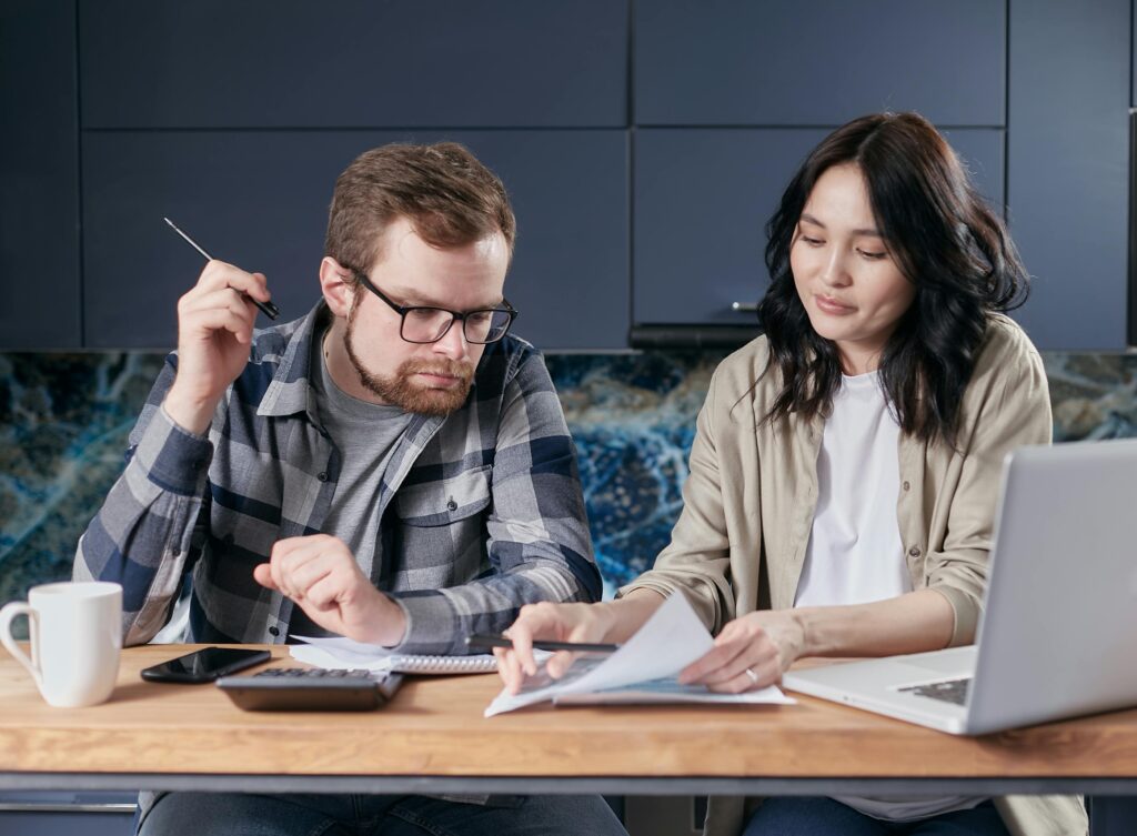 A couple is reviewing and calculating their household bills together at home.